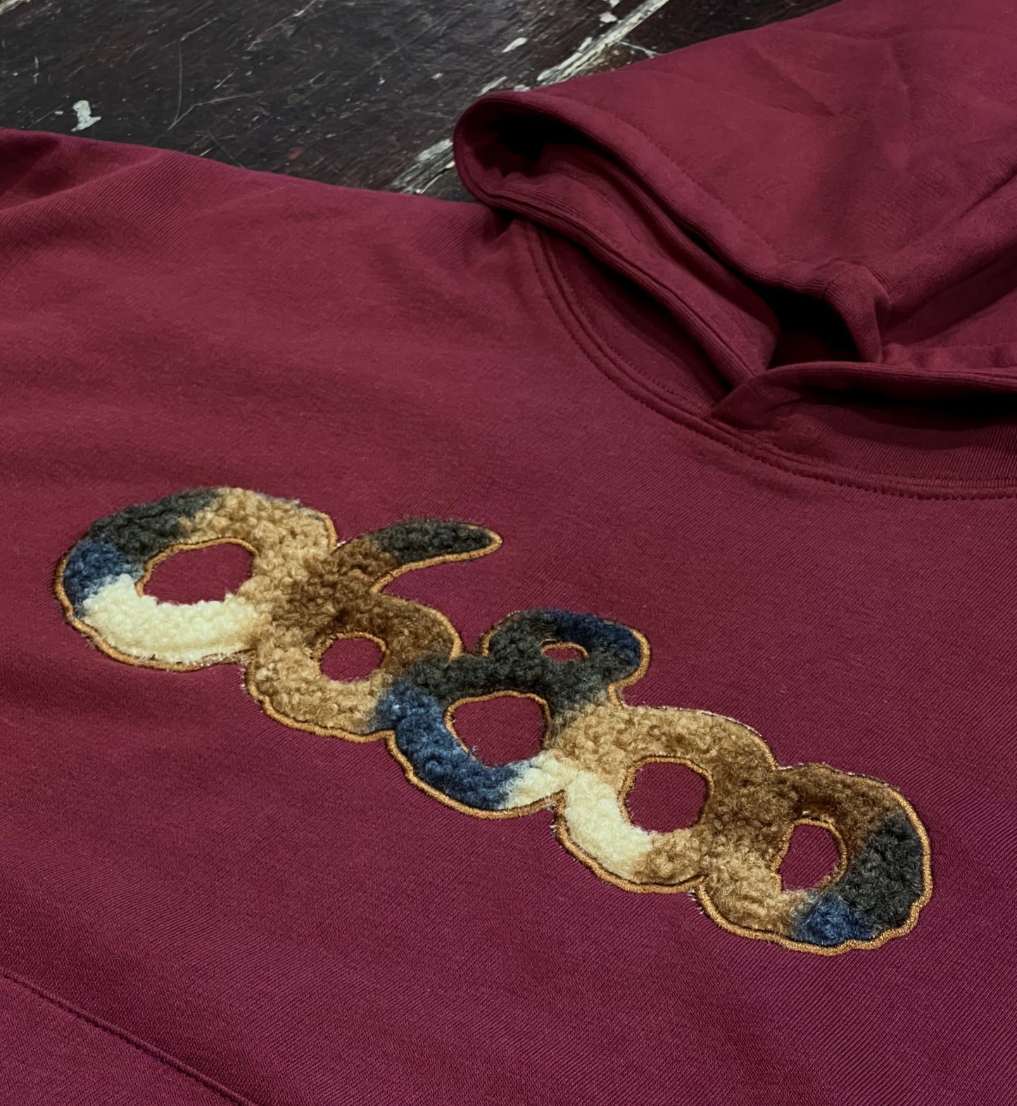 SUDADERA BURDEOS CON TELA DE BORREGUITO A CUADROS Y BORDADO