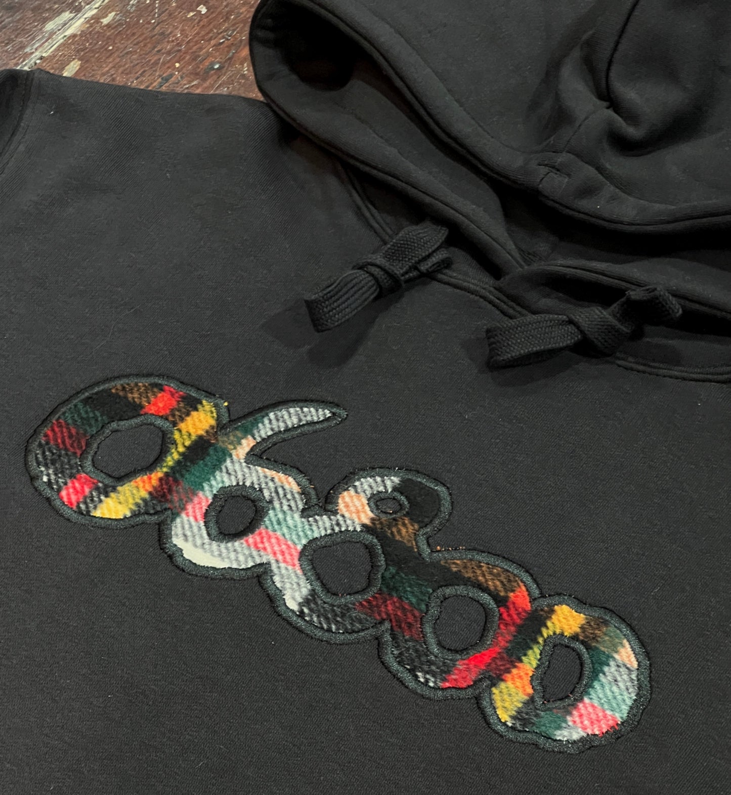 SUDADERA NEGRA CON TELA A CUADROS Y BORDADO